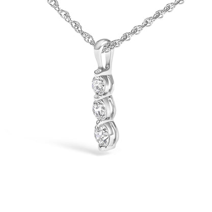 Close-up angled view of a white necklace pendant with three round white gemstones in prong settings suspended from a twisted chain.