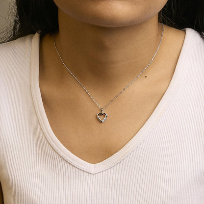Close-up front view of a model wearing a white metal necklace with a heart-shaped pendant featuring three round white gemstones in prong settings on one side.