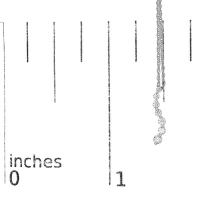 White metal necklace with a pendant of seven round white gemstones in prong settings, displayed vertically on a ruler for size reference, shot from the front.