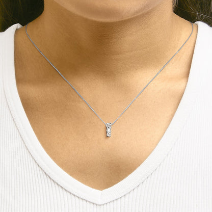 Close-up front view of a white metal necklace with three round white gemstones in a vertical row, worn on a model with a white V-neck top.