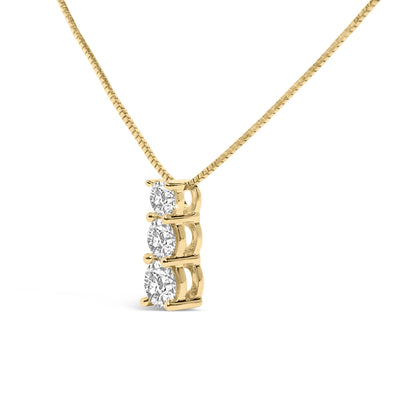 Close-up front angle of a yellow metal necklace with a vertical pendant featuring three round white gemstones in a shared prong setting.