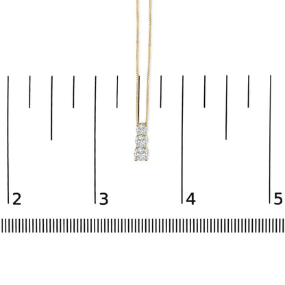 Yellow metal necklace with three vertically aligned round white gemstones in shared prong setting, shown on a measuring scale, front view.