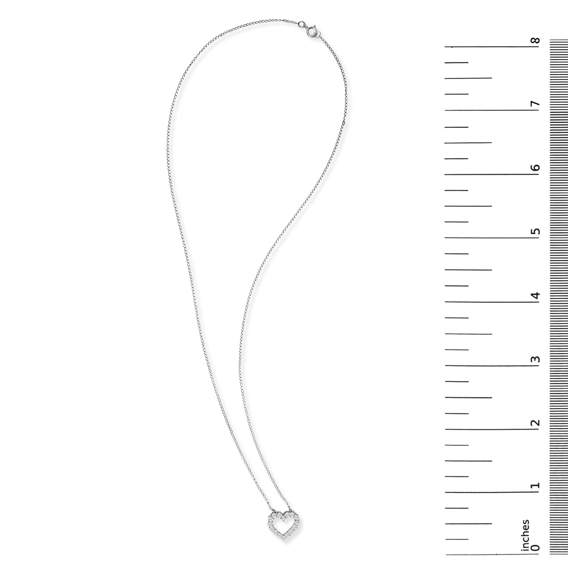 White metal necklace with a heart-shaped pendant adorned with round white gemstones in shared prong settings, shown flat on a white background next to a ruler scale.
