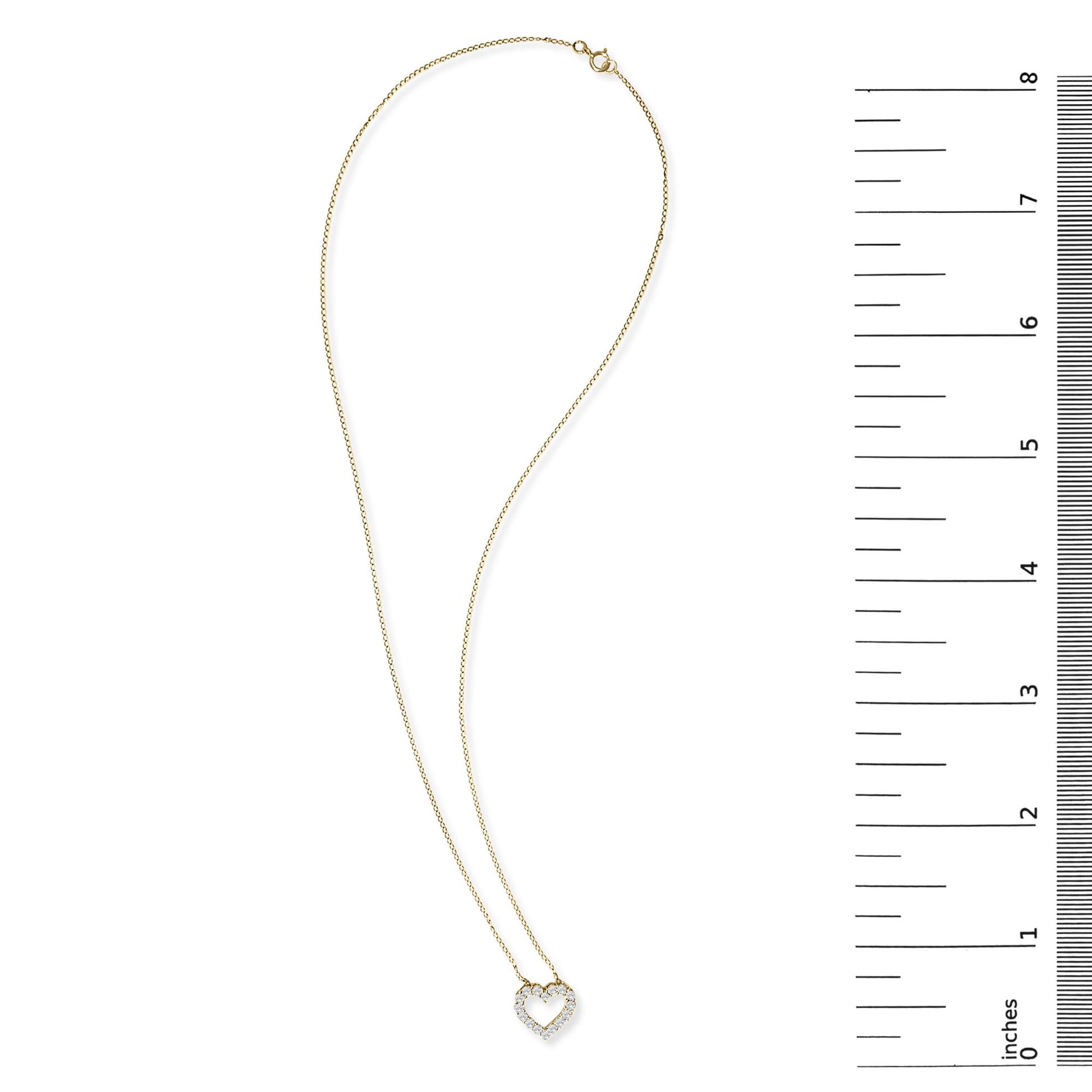 Yellow metal necklace with a heart-shaped pendant set with round white gemstones in a shared prong setting, shown flat on a white background next to a vertical ruler for scale.