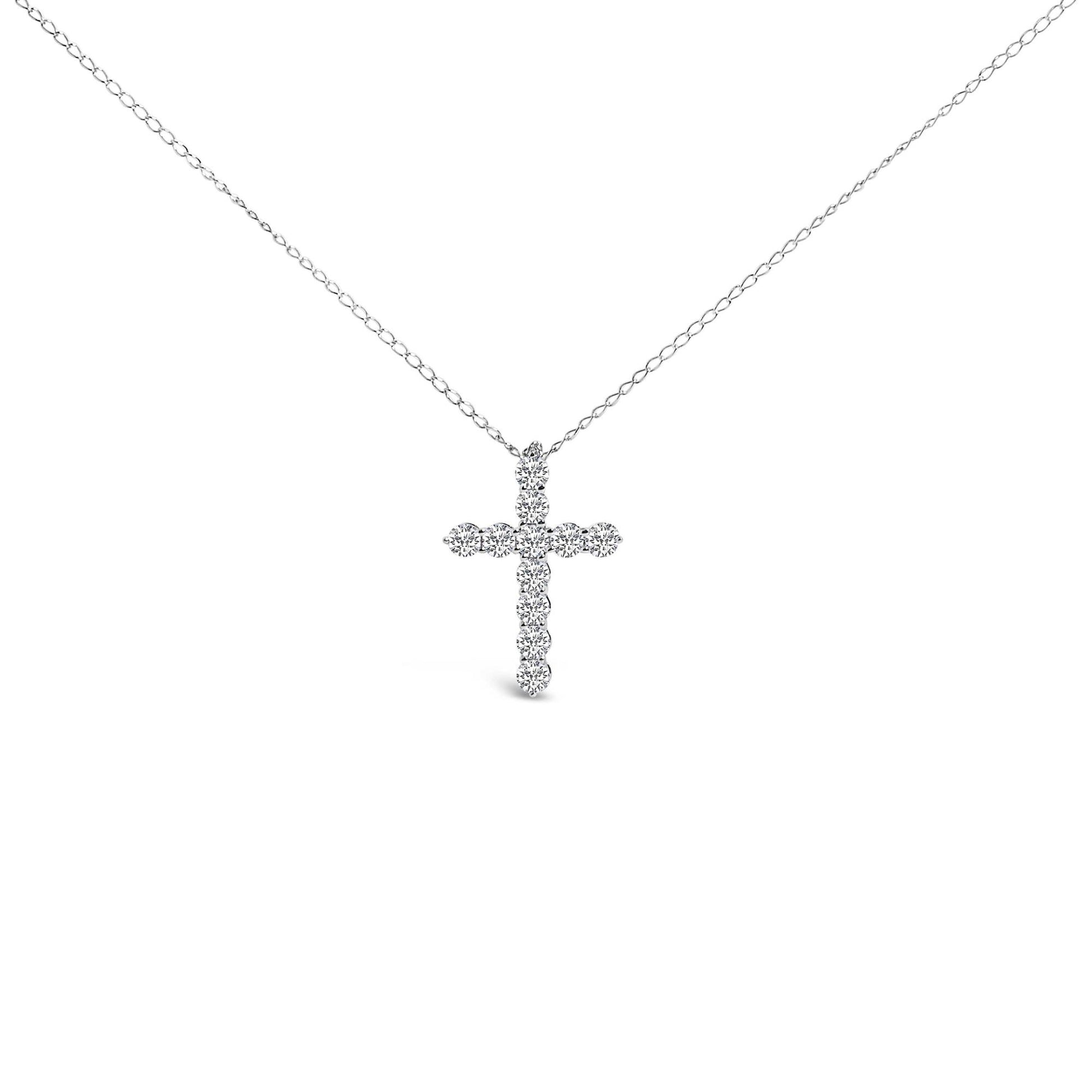 Front-facing shot of a white necklace with a cross-shaped pendant composed of round white gemstones in a shared prong setting.