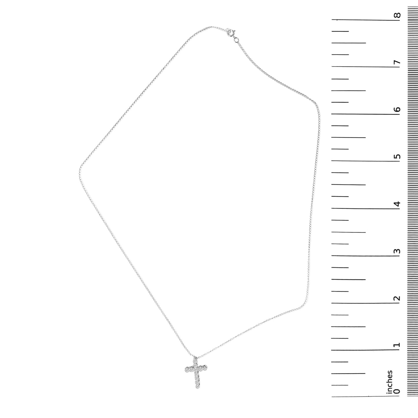 White necklace with a cross-shaped pendant featuring round white gemstones in shared prong settings, shown laid flat next to a ruler for scale, captured from a top-down angle.