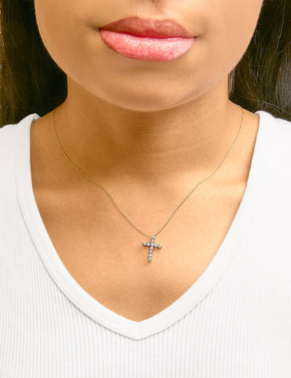 Necklace with yellow chain featuring a cross-shaped pendant set with round white gemstones, shown worn on a model from a front angle.