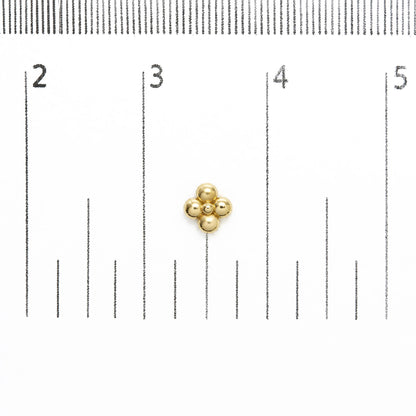 Yellow metal flower-shaped stud earring shown on a measurement scale, front view.