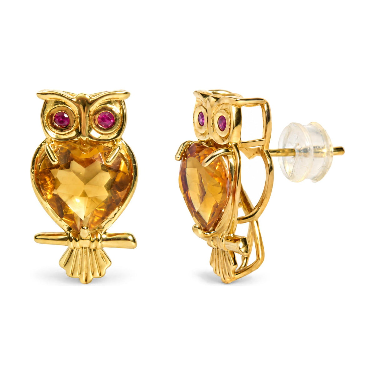Close-up front and side view of yellow metal owl-shaped earrings with heart-shaped yellow gemstones on the body and round red gemstones as eyes, shown on a white background.