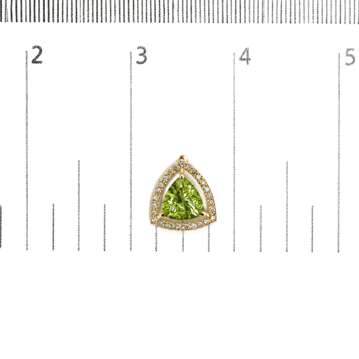 Close-up front view of a yellow metal earring with a green trillion-shaped gemstone surrounded by a halo of white round gemstones, shown against a scale background.