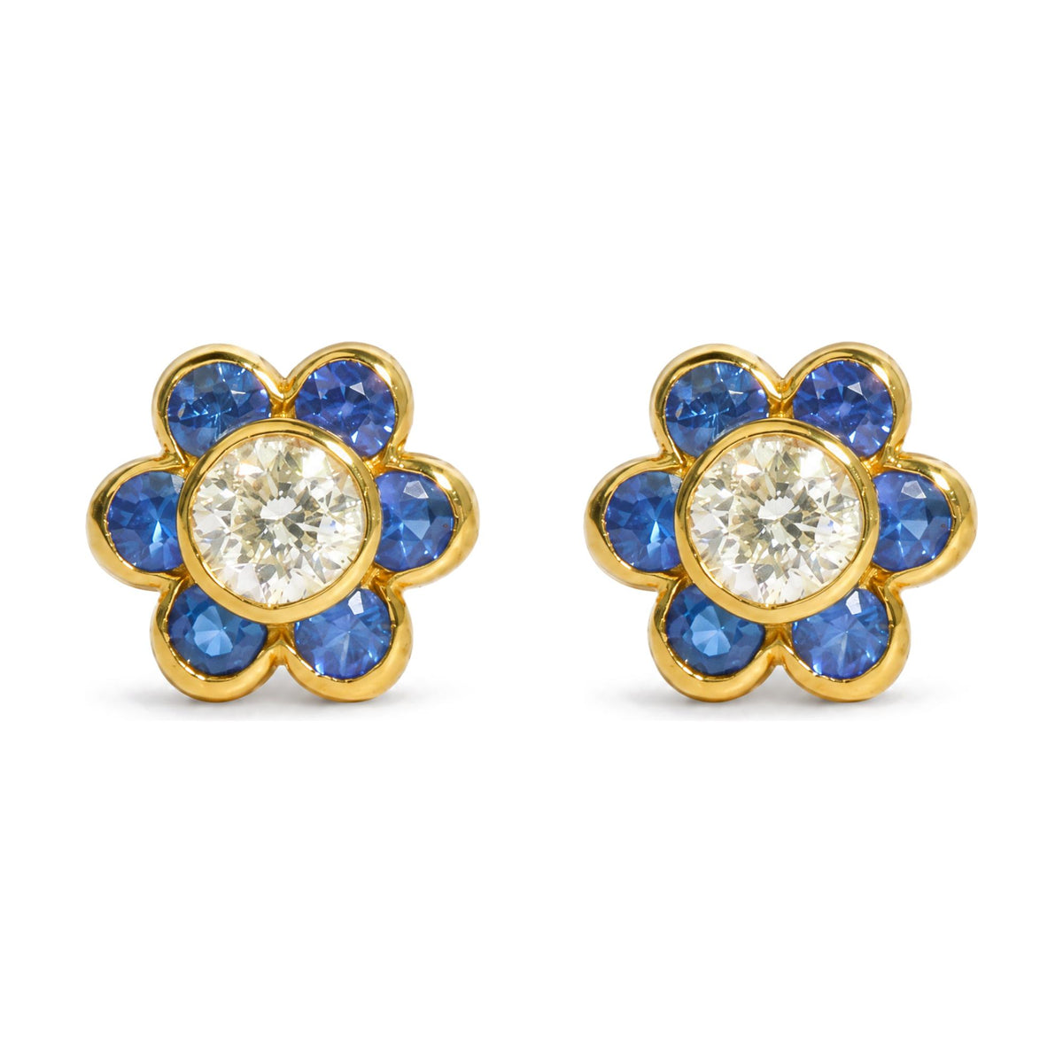 Close-up front view of pair of yellow metal flower-shaped earrings featuring a central round white gemstone surrounded by blue round gemstones in bezel settings, shown on a white background.