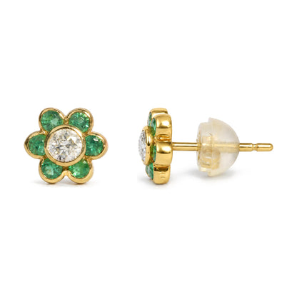 Close-up side front angle of a yellow metal flower-shaped stud earring with round white gemstone center and round green gemstones forming petals, shown on a clear earring back.