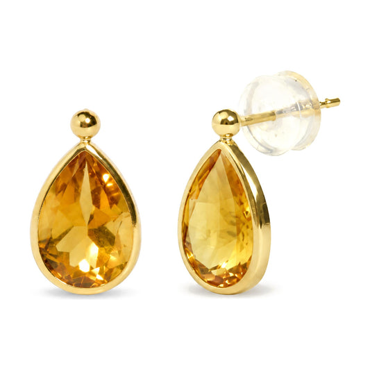 Close-up front angle of yellow metal earrings, each featuring a pear-shaped yellow gemstone in bezel setting, with one earring showing the back and clear earring clutch.