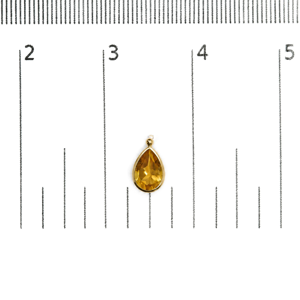 Close-up front view of a single yellow metal earring with a pear-shaped yellow gemstone in bezel setting, shown on a white background with a ruler for scale.