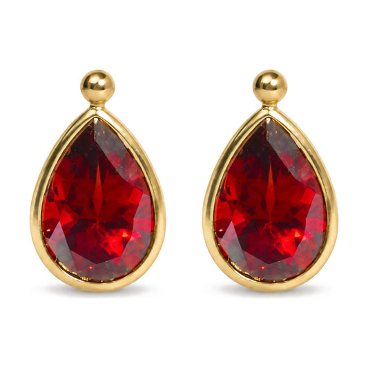 Close-up front view of yellow metal earrings with pear-shaped red gemstones in bezel settings.