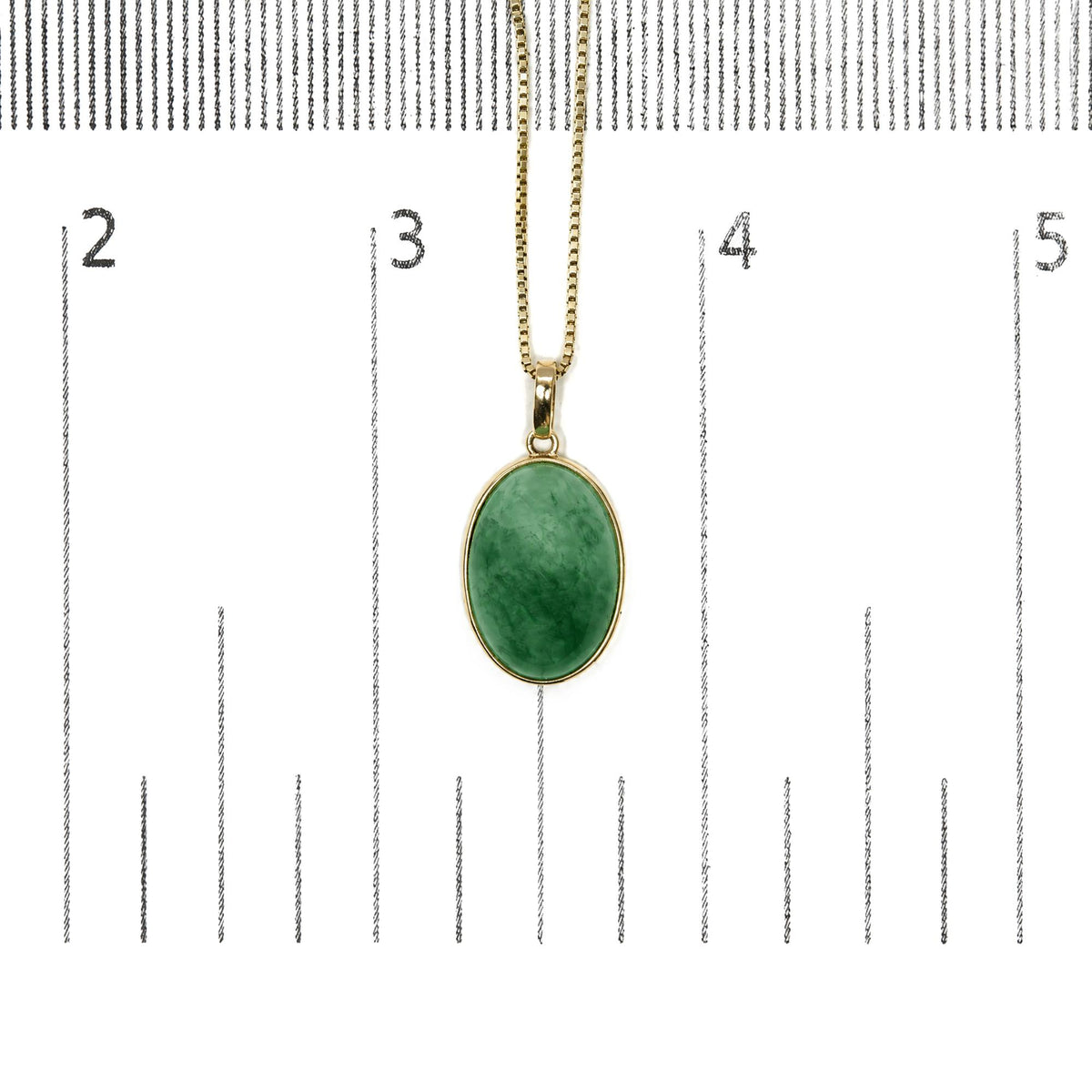 Yellow necklace with an oval green gemstone in bezel setting, photographed from the front on a scale.