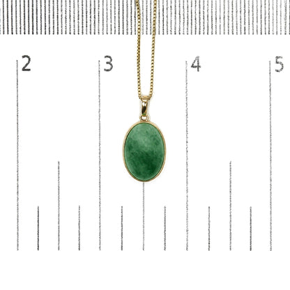 Yellow necklace with an oval green gemstone in bezel setting, photographed from the front on a scale.