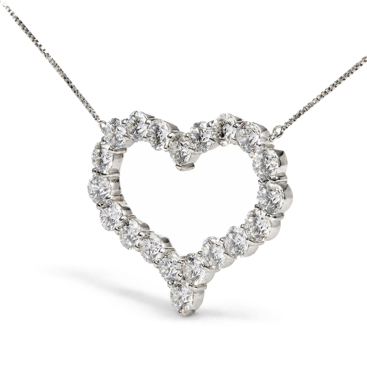 Close-up front angle of a white metal heart-shaped necklace pendant featuring round white gemstones in prong settings along the outline, shown on a white background.