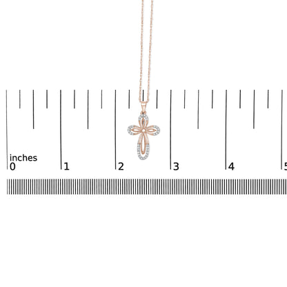 Rose-colored necklace with a cross-shaped pendant featuring round white gemstones in prong settings, shown hanging against a ruler scale, front view.
