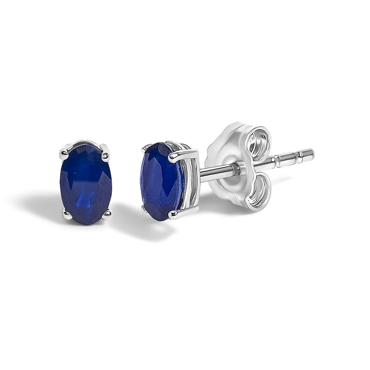 Close-up front angle of white metal stud earrings with oval-shaped blue gemstones in four-prong settings shown on a white background.