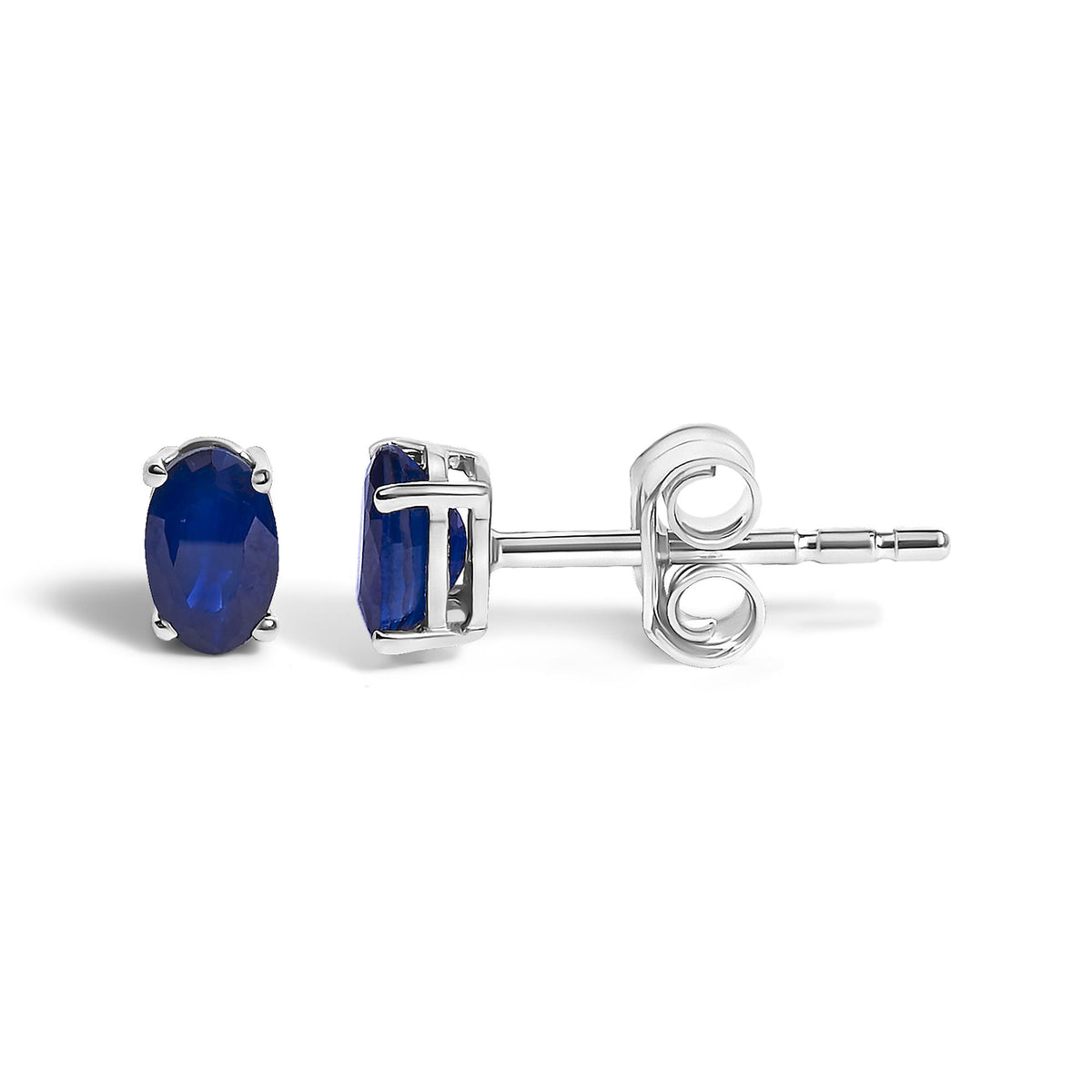 Close-up side and front view of a pair of white metal stud earrings with oval-shaped blue gemstones in four-prong settings on a white background.