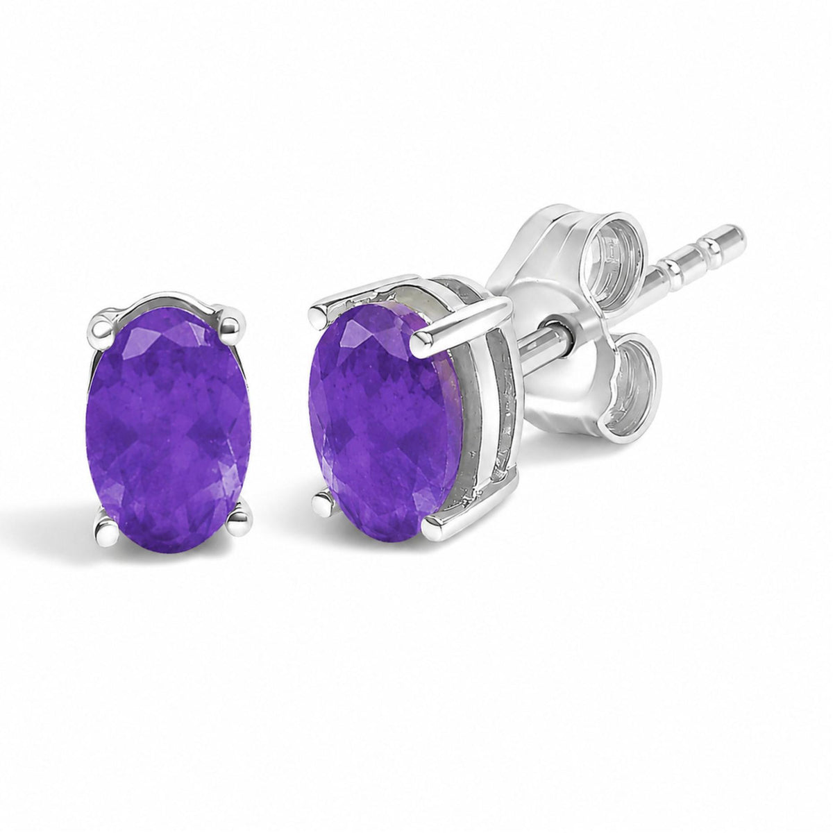 Close-up angled view of a pair of white metal stud earrings featuring oval-shaped purple gemstones in four-prong settings.