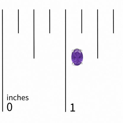 Close-up front view of oval-shaped purple gemstone stud earrings set in white metal, shown on a scale marked in inches.