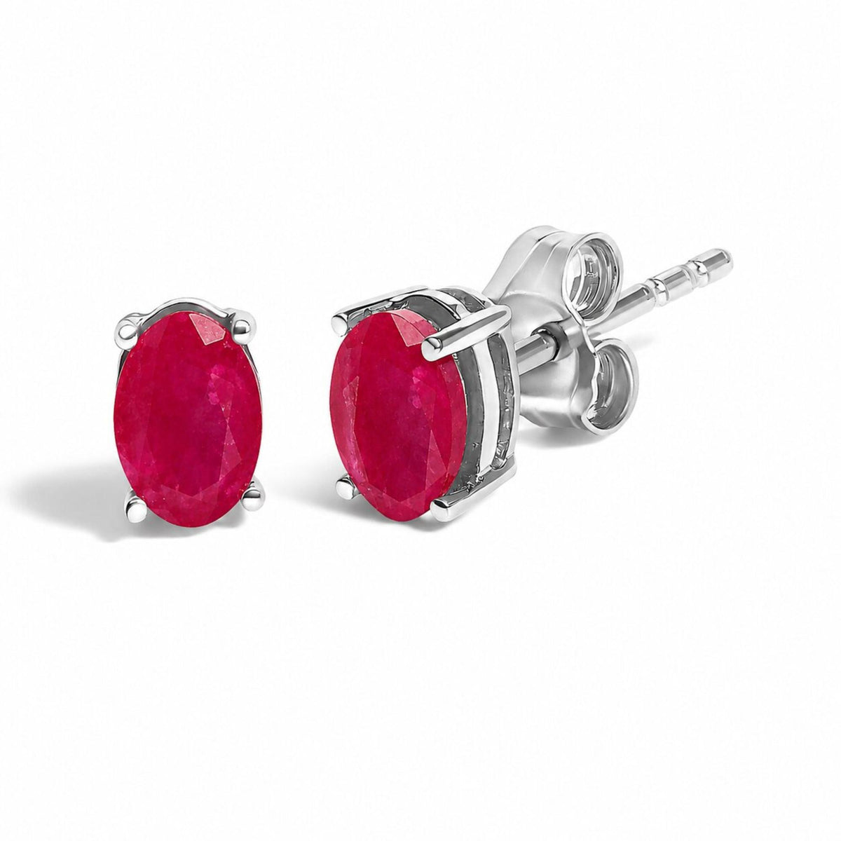Close-up front angle of a pair of white metal stud earrings with oval red gemstones in 4-prong settings.