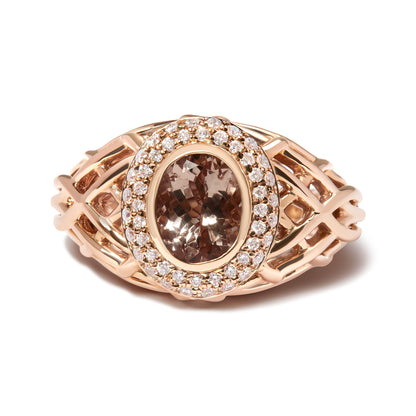 Rose metal ring with an oval pink gemstone in a bezel setting surrounded by a double halo of white round pave-set gemstones, shown from a front-facing close-up angle.