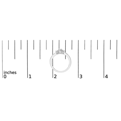 White metal ring shown on a scale, side view, featuring one round white gemstone in a four-prong setting flanked by two round white gemstones in four-prong settings and a row of round white gemstones in a channel setting on each side.