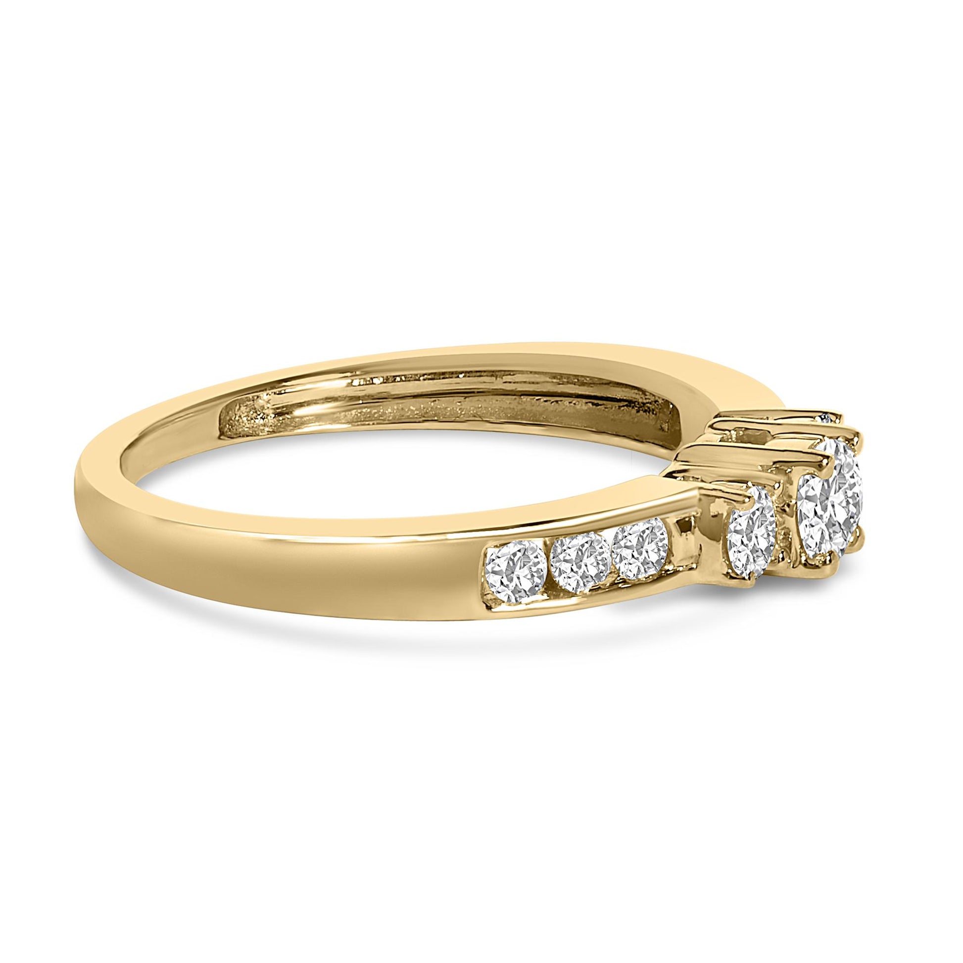 Side angle view of a yellow ring featuring a central round white gemstone held by four prongs, two smaller round white gemstones in four-prong settings on one side, and a row of round white gemstones in a channel setting along the band.