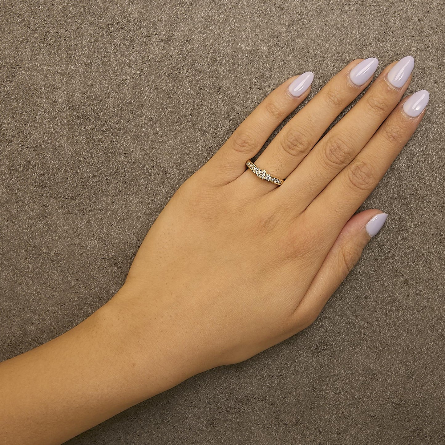 Yellow metal ring with round white gemstones in 4-prong and channel settings, shown worn on a model's hand from a top angle.