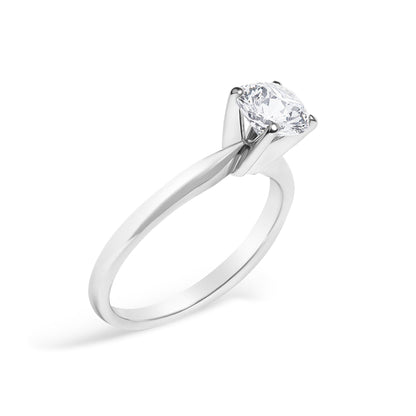 Close-up angled shot of a white metal ring with a round white gemstone set in a 4-prong setting.