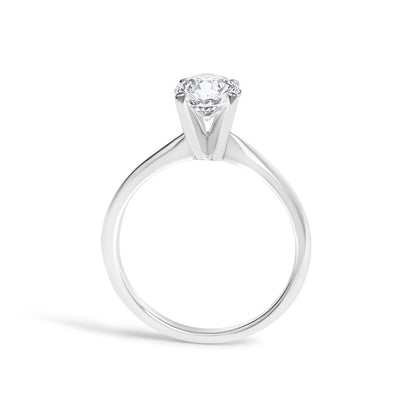 Close-up front angle of a white metal ring with a single round white gemstone set in a four-prong setting.