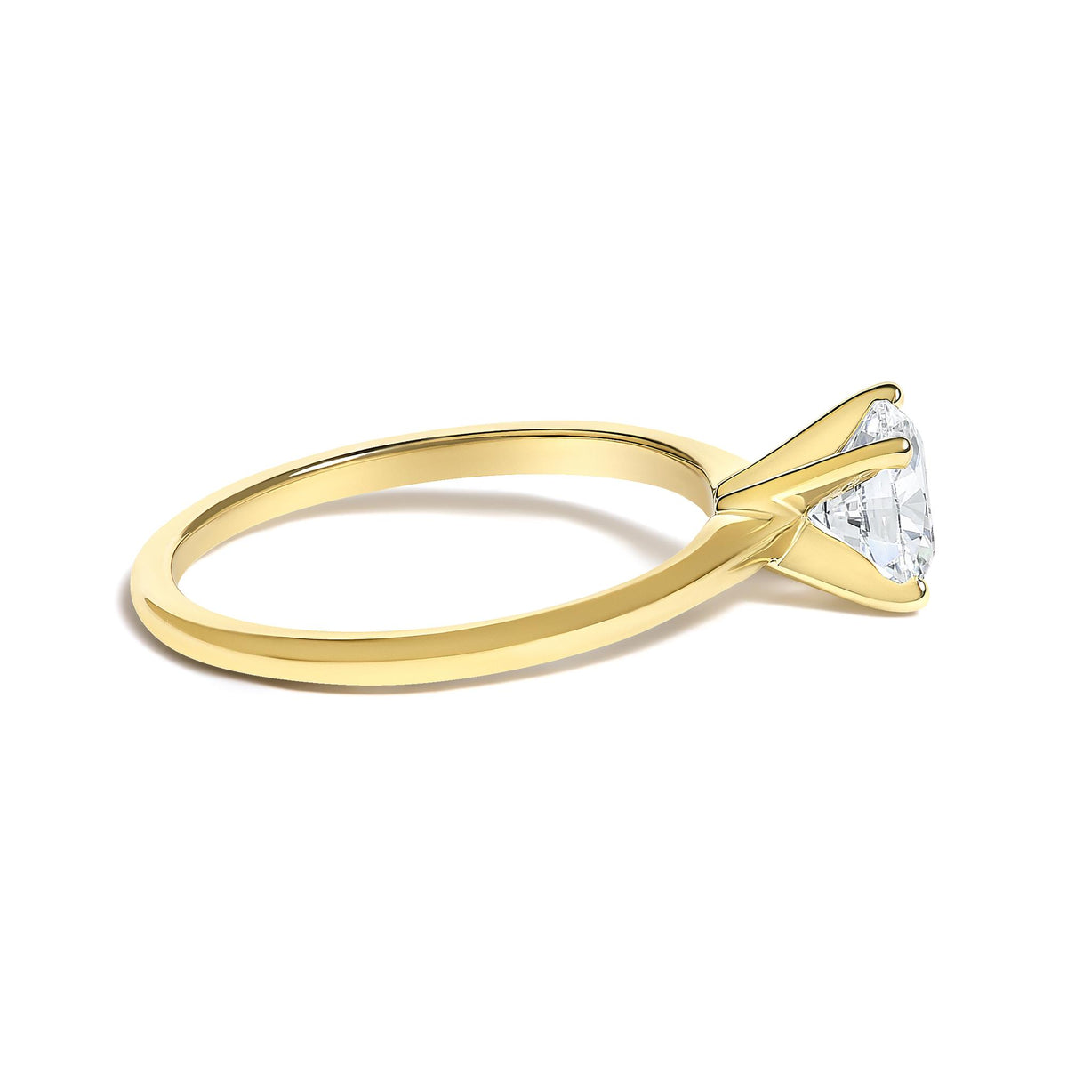 Close-up angled side view of a yellow metal ring with a round white gemstone held by a four-prong setting.