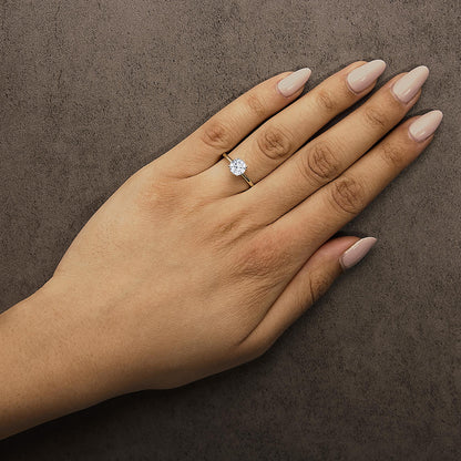 Yellow ring with a round white gemstone in a 4-prong setting, shown worn on a model’s hand from a top angle.