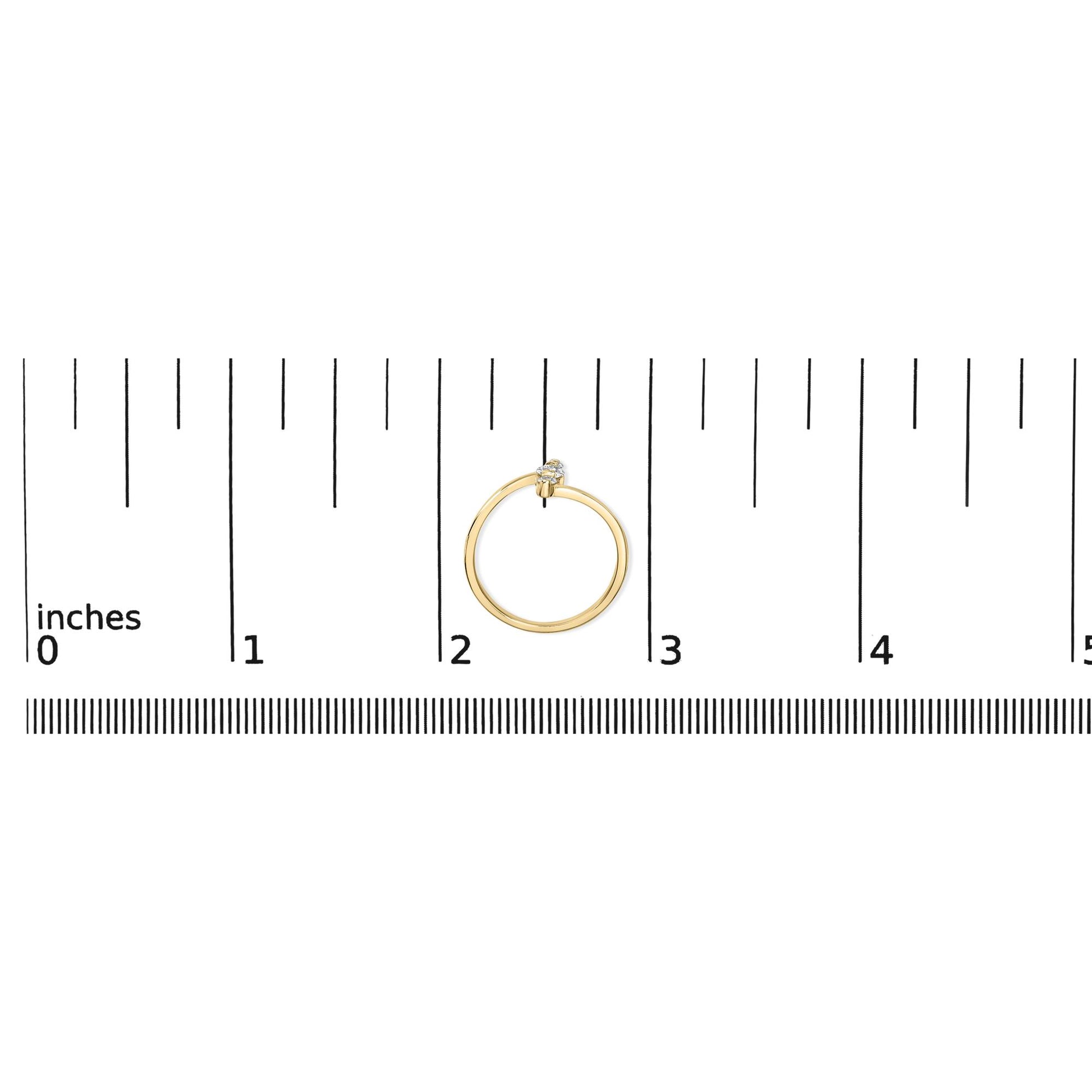 Yellow metal ring with one white round gemstone and two smaller white round gemstones in shared prong settings, shown flat on a measurement scale from a top-down angle.