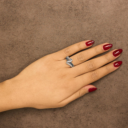 White metal ring with intertwined bands featuring round blue and white gemstones in prong settings, shown worn on a model's hand from a top-down angle.