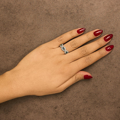 Ring with yellow and white metal featuring three blue gemstones in bezel settings and surrounding white gemstones in prong settings, shown worn on a model's hand from a top angle.