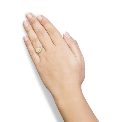 Close-up of a two-tone ring with a round shape white gemstones in a shared prong setting forming a heart design, worn on a model's finger, shot from above.