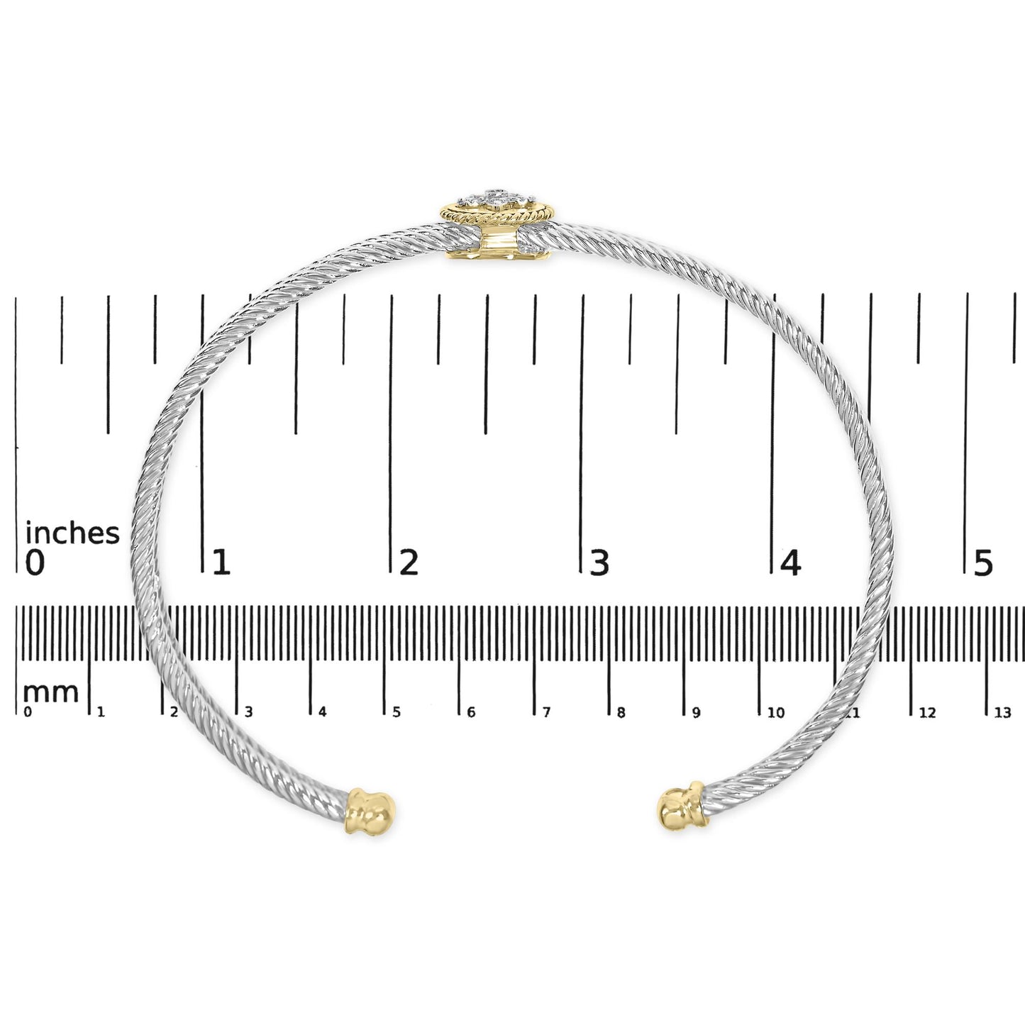 Open-ended bracelet in yellow and white metal with a twisted design, featuring a cluster of white round gemstones at the clasp, shown flat on a ruler for size reference, top-down view.