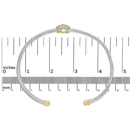Open-ended bracelet in yellow and white metal with a twisted design, featuring a cluster of white round gemstones at the clasp, shown flat on a ruler for size reference, top-down view.
