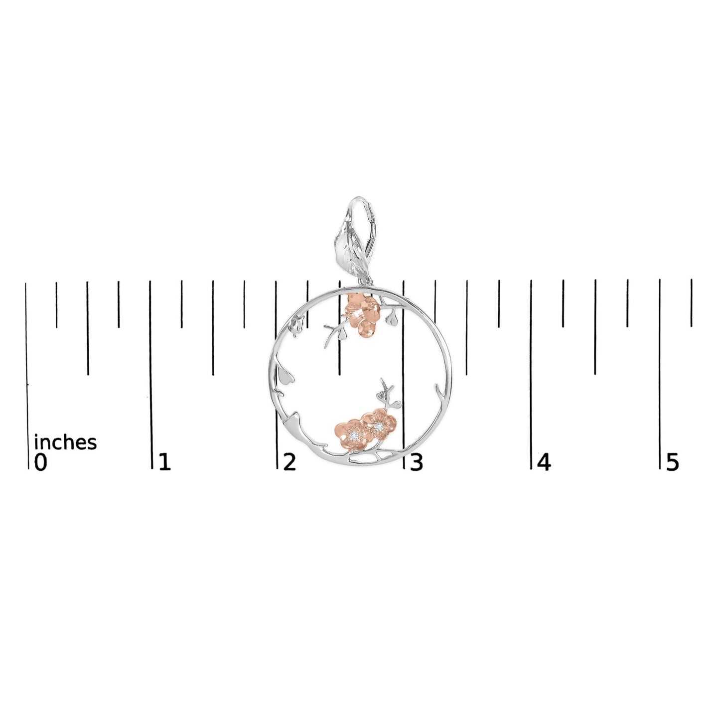 Top-down view of a circular earring with white and rose metal colors, featuring floral accents with white gemstones, placed on a ruler for size reference.