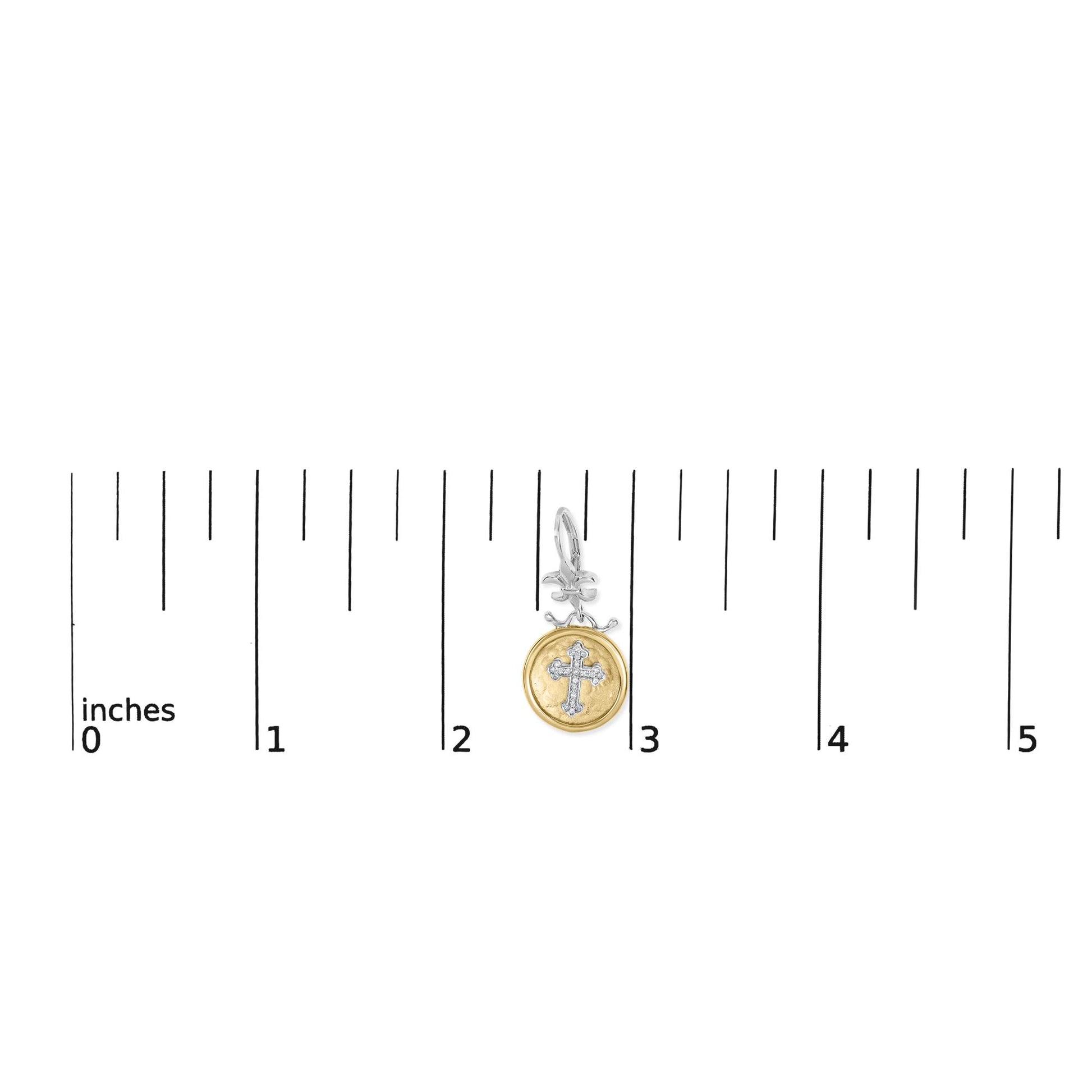 Earring with yellow and white metal featuring a cross design with white gemstones, shown from the front on a ruler for size reference.