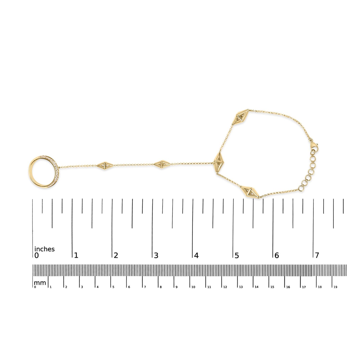 Yellow metal bracelet with geometric shapes and a pave-set round white gemstone ring, shown flat on a ruler for size reference, shot from above.