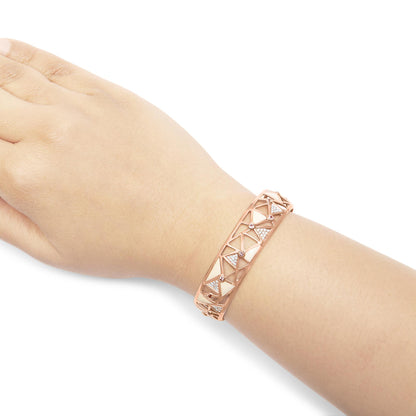 Rose-colored bracelet with geometric cutout design, featuring white gemstones in pave setting and pink round gemstones in bezel setting, shown on a model's wrist from a top-side angle.