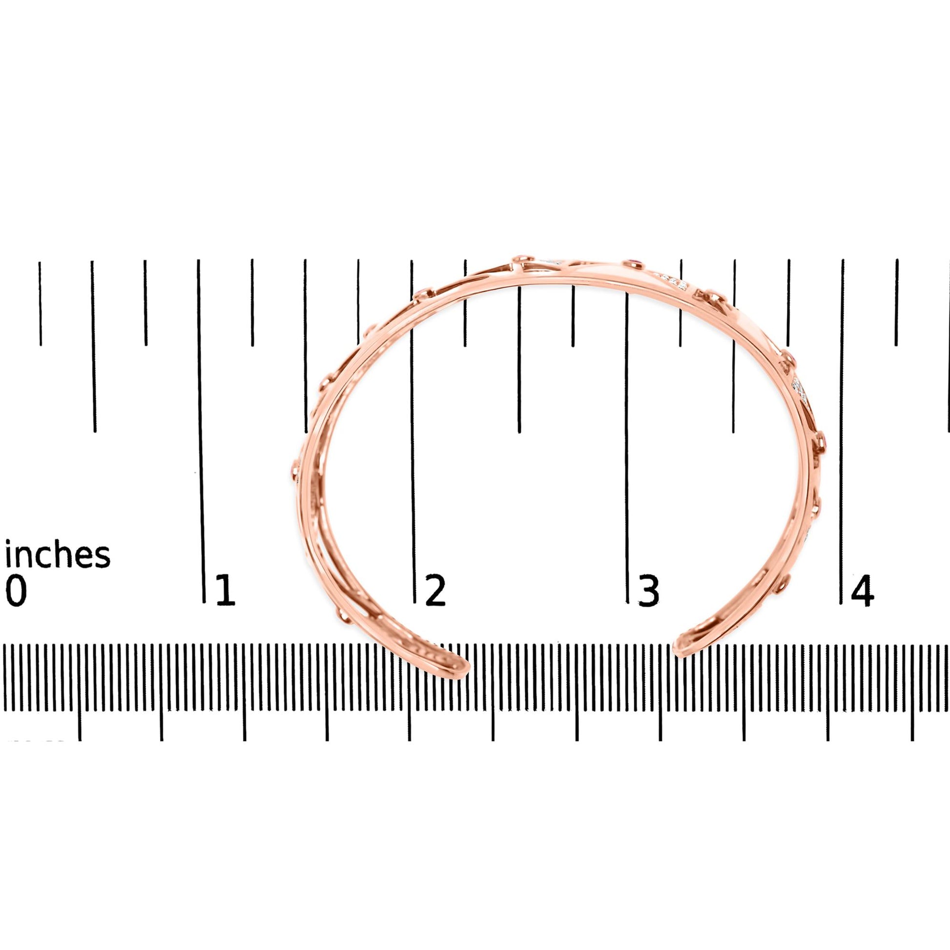 Rose metal open cuff bracelet with round pink bezel-set gemstones and white pave-set gemstones, shown from top angle on a ruler for size reference.