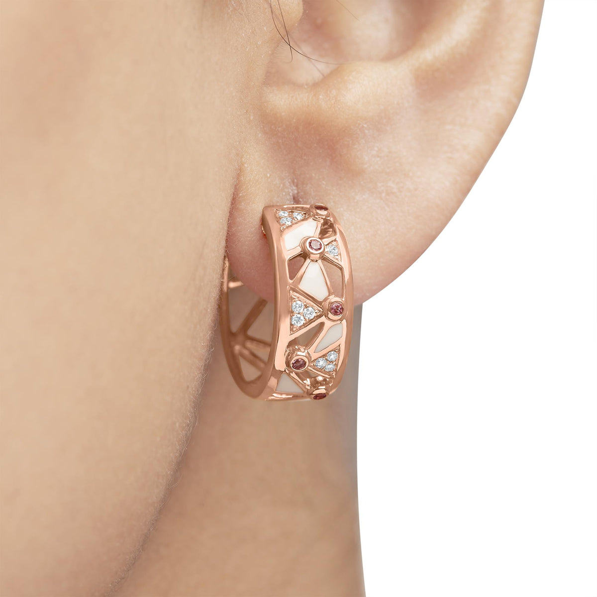 Close-up of 14K rose gold geometric hoop earring showcasing diamond, pink tourmaline, and white enamel on an ear
