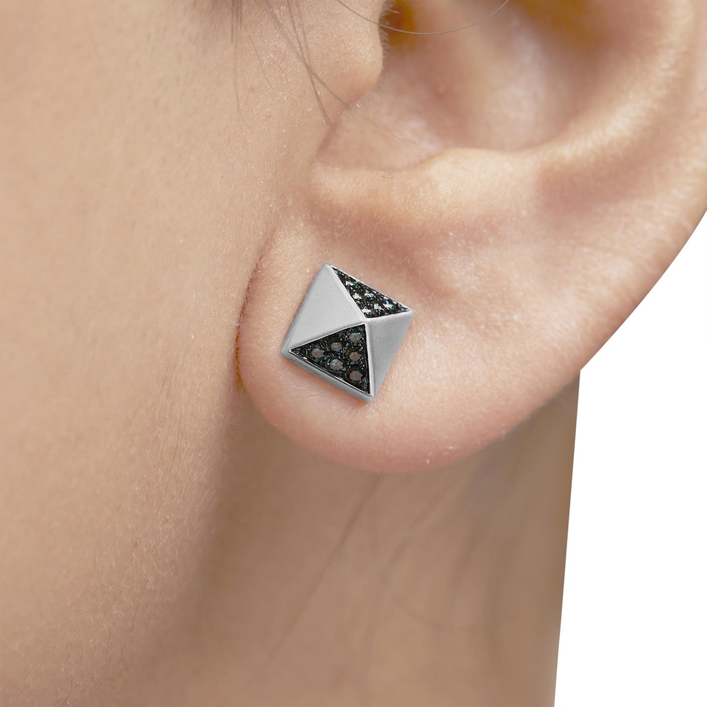 Close-up side view of a white metal geometric stud earring with two triangular sections each inset with multiple round blue gemstones, worn on a model's ear.