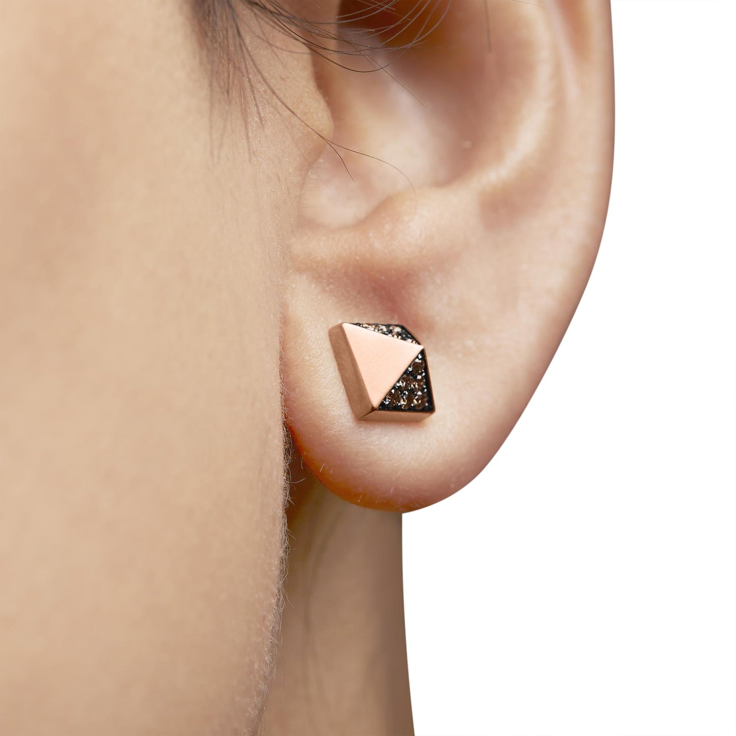 Close-up side view of a rose metal geometric stud earring with small brown round prong-set gemstones, worn on a model's ear.